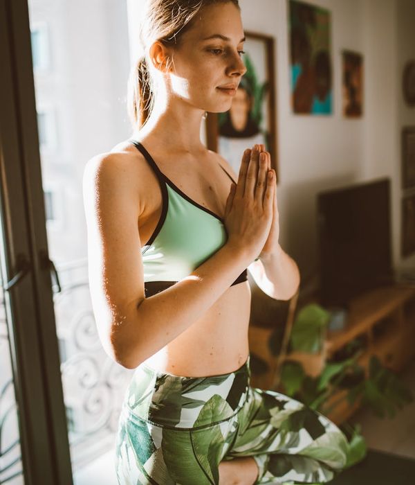 Woman in a focused yoga pose, surrounded by calm pear green light.
